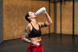 Tattooed fit woman drinking water
