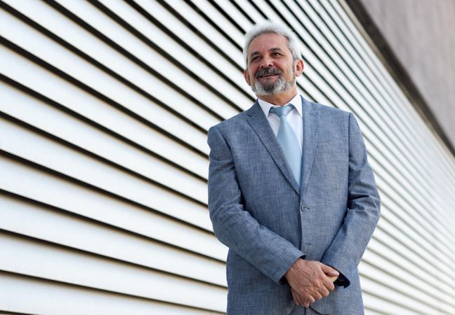 Portrait of a content businessman standing next to lined wall