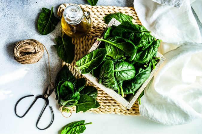 Top view of fresh spinach salad served with oil on rattan placemat