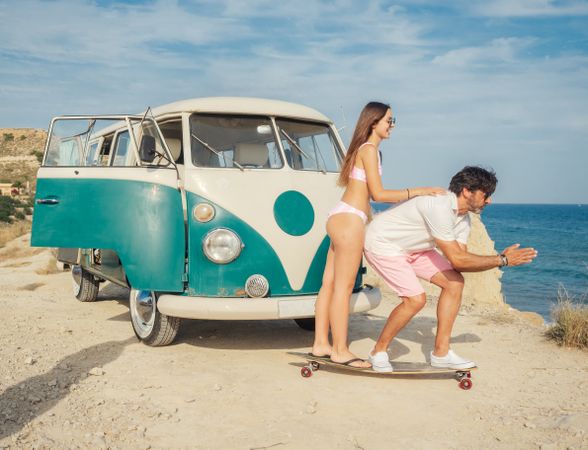 Man and woman on a longboard near trailer