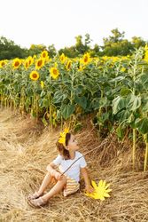 Cute child in blooming sunflower field
