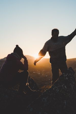 Man and woman enjoying sunset in autumn mountains