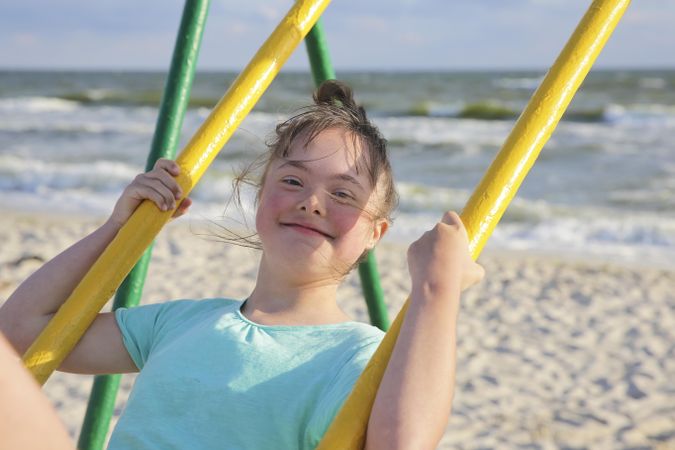 Happy young child swinging on swing set at beach