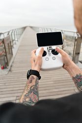 Man with remote for drone on boardwalk on beach