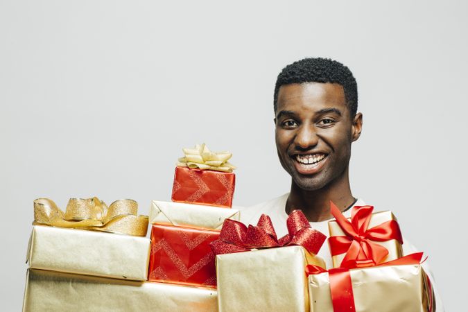 Portrait of smiling Black man behind many wrapped presents