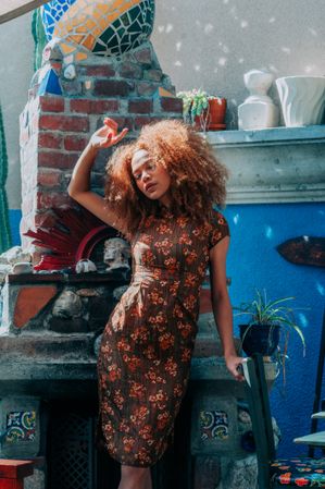 Full length fashion photo of woman holding arm up to cover face from sun