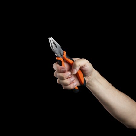 Hand holding pliers on a dark background.