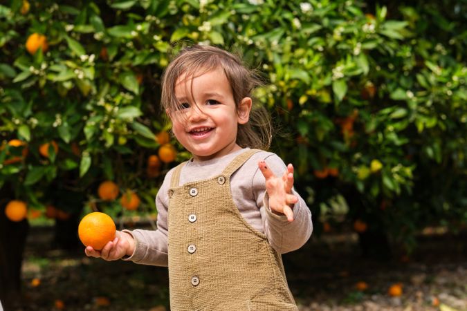Cheerful girl with ripe orange in garden