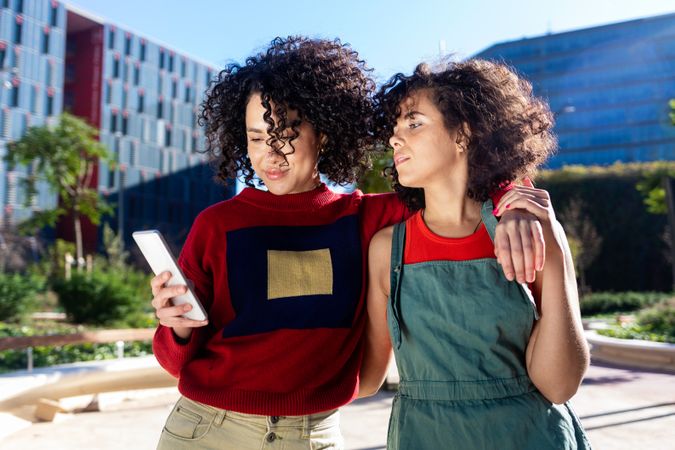 Female couple looking at smartphone together outside