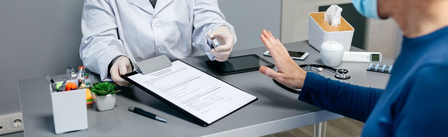 Patient refusing the coronavirus vaccine offered by doctor