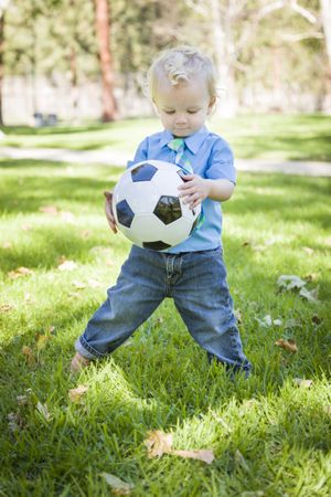 Young Cute Boy Playing with Soccer Ball in Park