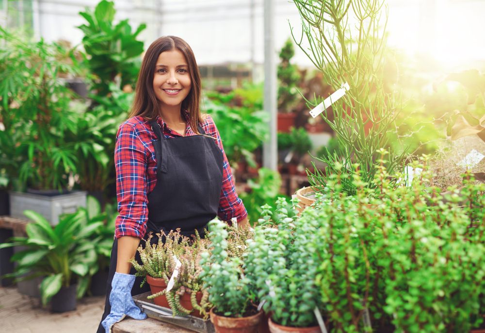 Proud woman standing at table with terra-cotta planters in a greenhouse