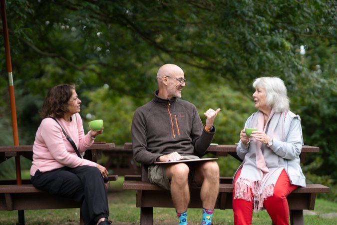 Two women enjoying tea with art instructor outside
