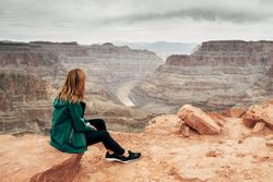 Female relaxing on cliff and admiring picturesque view