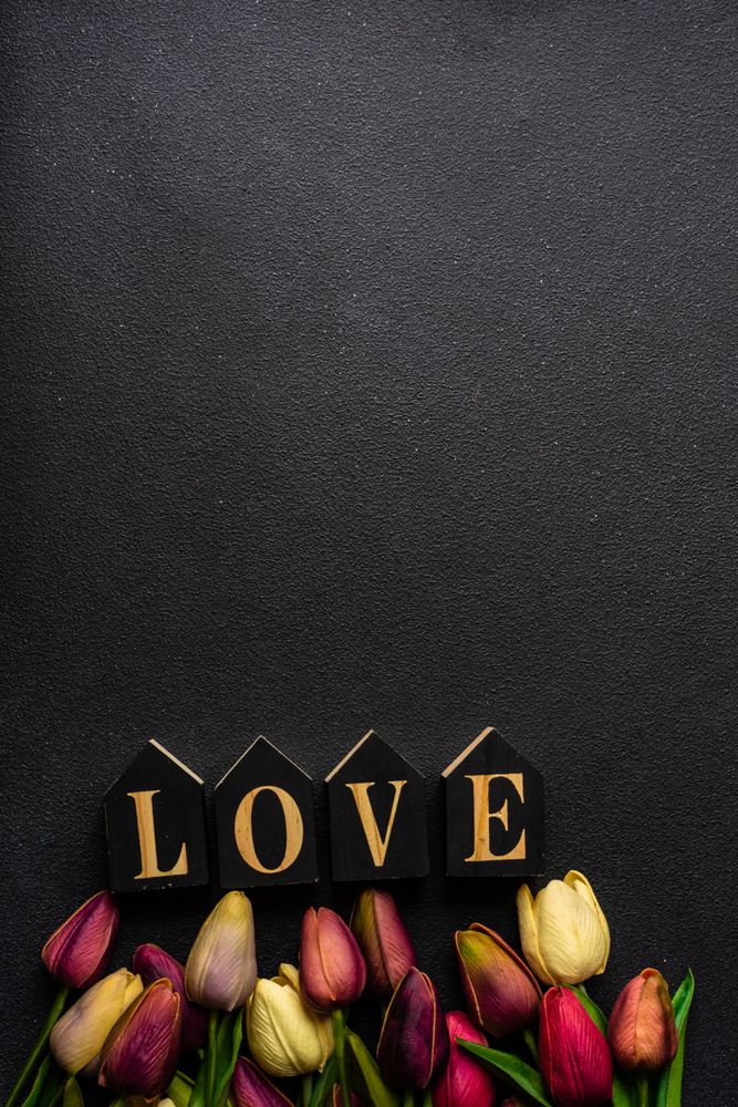 Tulips and the word "love" on dark table