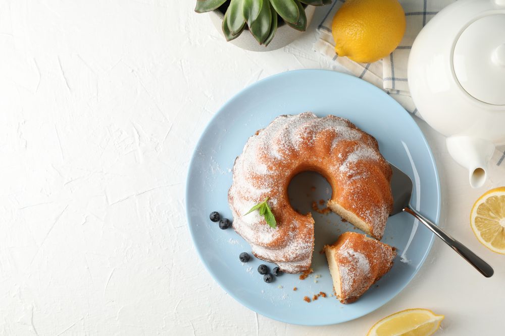 Cake with powdered sugar, blueberry and mint on blank background, top view