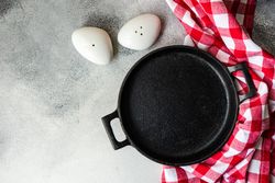 Empty iron cast pan with checkered red napkin with salt & pepper shakers