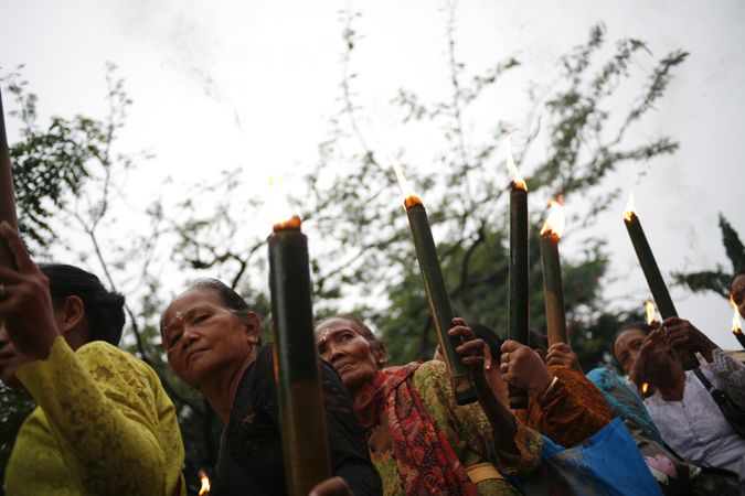 Group of older Indonesian Hindu women with torches with lit flames marching during Nyepi day
