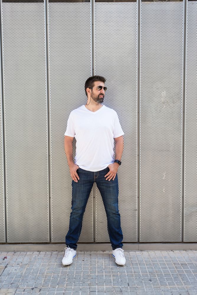 Latino man in sunglasses leaning against wall outside