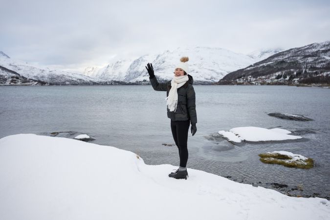 Young asian woman on pond shore against highland in winter
