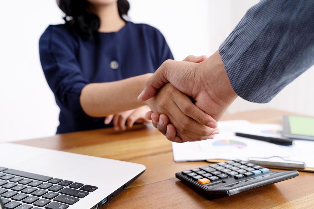 Business Handshake Between Two Professionals Over a Financial Desk Meeting