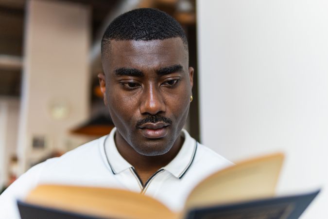 Serious Black male reading book in cafeteria