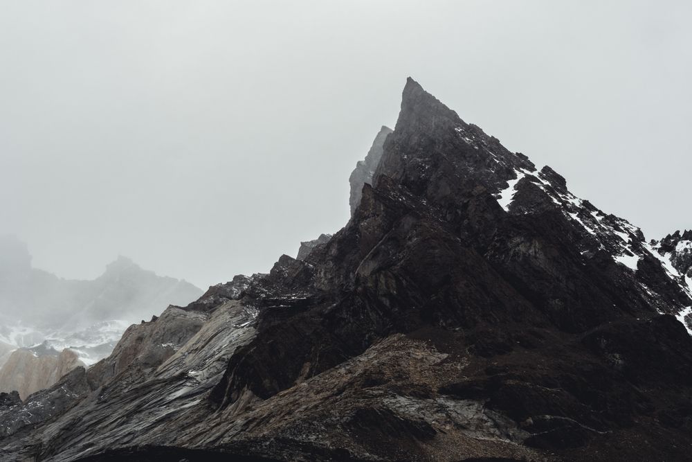 Harsh mountain snowy peak shrouded in fog