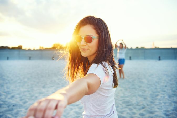 Portrait of brunette woman with her arm out with friends in background on beach