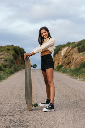 Joyful woman standing with longboard