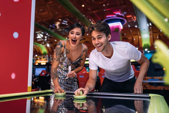 Excited man and woman having fun playing games at a gaming arcade
