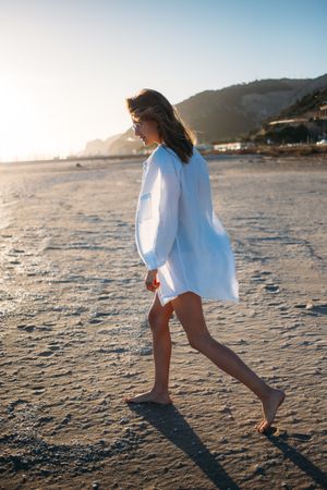 Woman walking on beach in oversized shirt