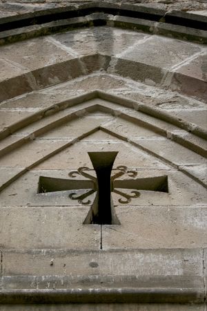 A real Spanish door with a cross. Catholic cross in Gothic style on a historical building