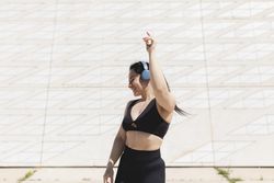 A young woman, dancing and moving, happy, while listening to music with headphones and disconnecting, to relax, after exercising