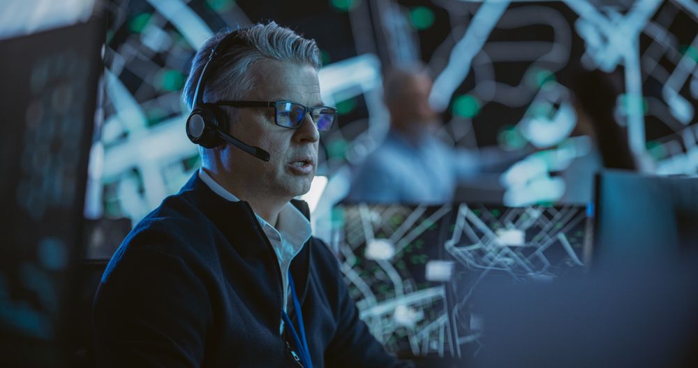 Portrait of a Logistics Officer Wearing a Headset, Working in a Central Office Hub for Delivery Operations, Control and Monitoring for Managing International Fleet of Drivers