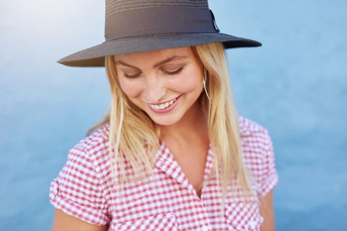 Close up of woman in hat and red checkered shirt smiling and looking down
