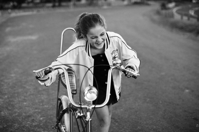 Grayscale photo of young girl riding bicycle