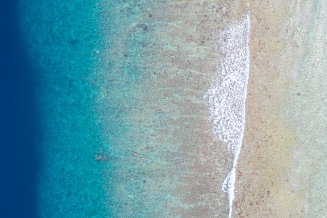 Aerial shot of clear water washing ashore