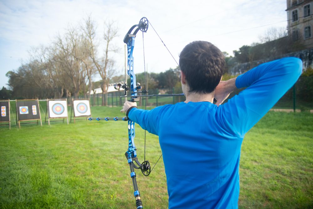 Back view of young man about to shoot with bow and arrow