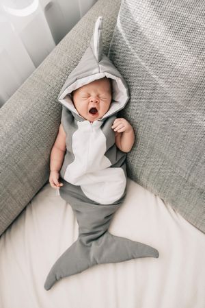 Baby in shark costume sleeping on couch