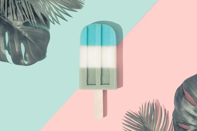 Ice cream popsicle in pastel blue on paper duotone background with tropical palm leaves