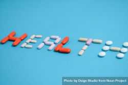 Various pills spelling the word "HEALTH" on blue background 56G2wN