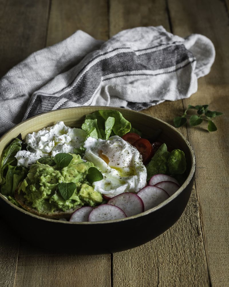Tasty avocado bowl with vegetables on table
