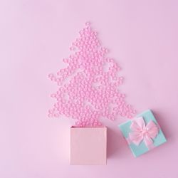 Christmas tree made of pink star decoration with blue gift box on pastel pink background