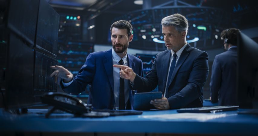 Two Successful Stock Exchange Brokers Using Tablet Computer, Talking About Asset Management Strategy for an International Business Client