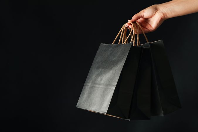 Female hand hold paper bags on dark background