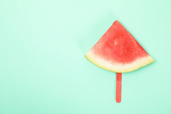 Watermelon slice on ice cream stick on mint background. Summer fruit