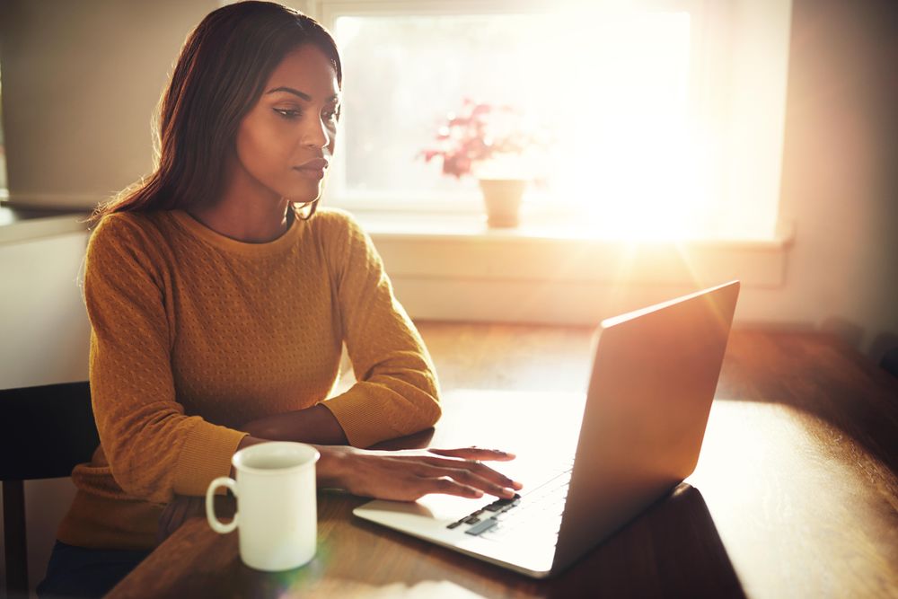 Woman on laptop in sunny room