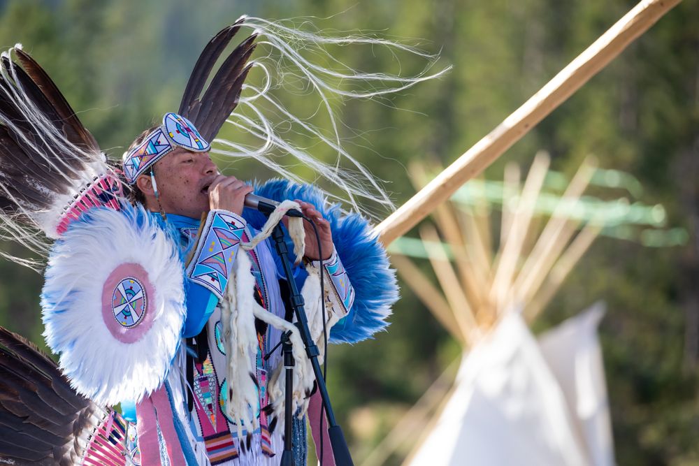 Montana, United States - August 17, 2022: Native man in full regalia performing with microphone