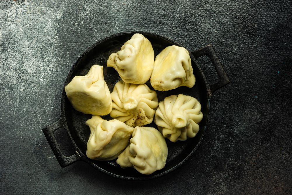 Top view of iron cast pan of traditional Georgian khinkali dumplings on kitchen counter