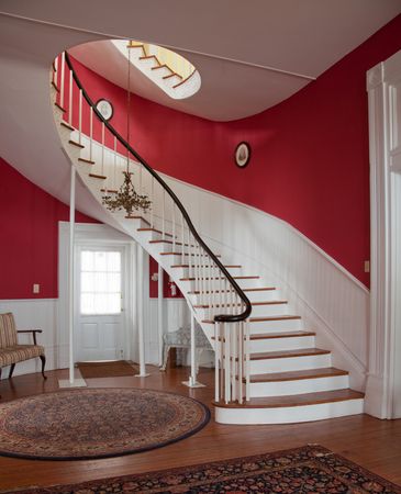 Sweeping curved staircase with red walls in historic mansion in Alabama